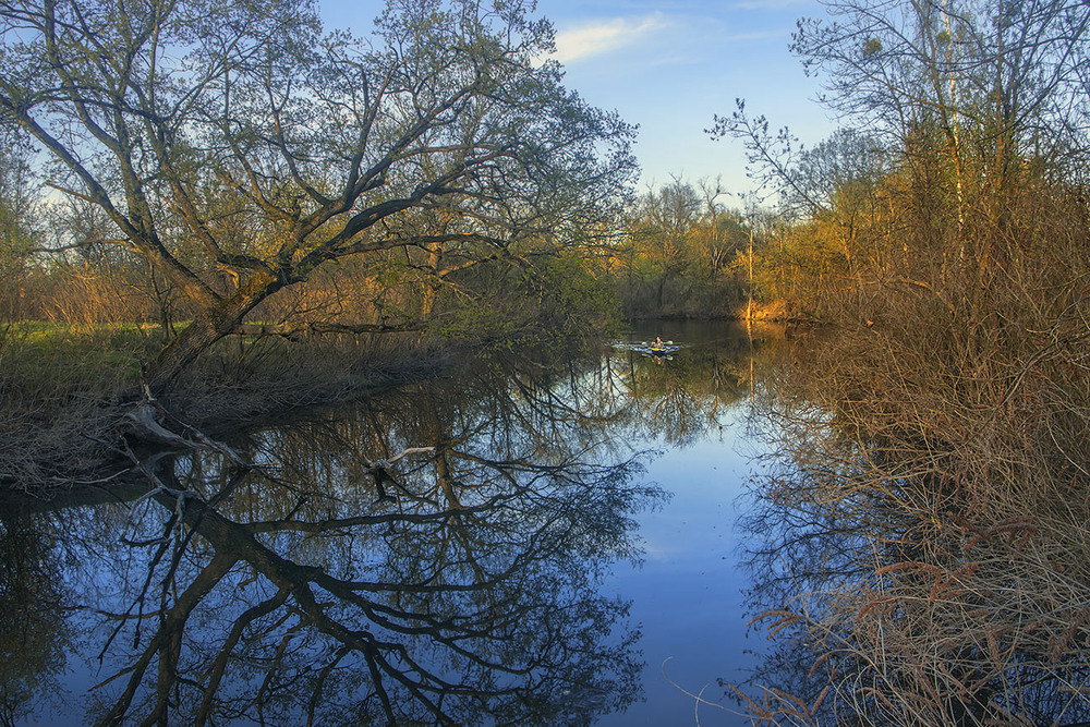Фотографія Квітнева річка Коник в Києві наприкінці дня: спокій і байдарка линуть над мокрим дзеркалом. / Юрій Максименко / photographers.ua
